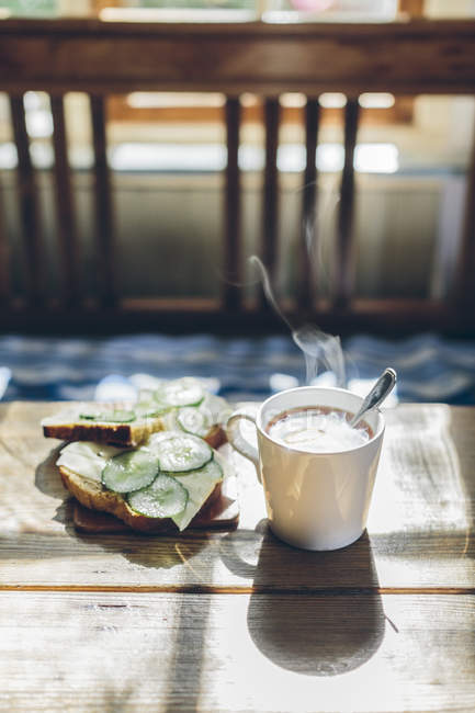 Gros plan du café dans une tasse blanche et sandwich au fromage et aux concombres — Photo de stock