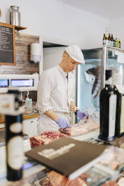 Carnicería que desenvuelve carne en la carnicería - foto de stock