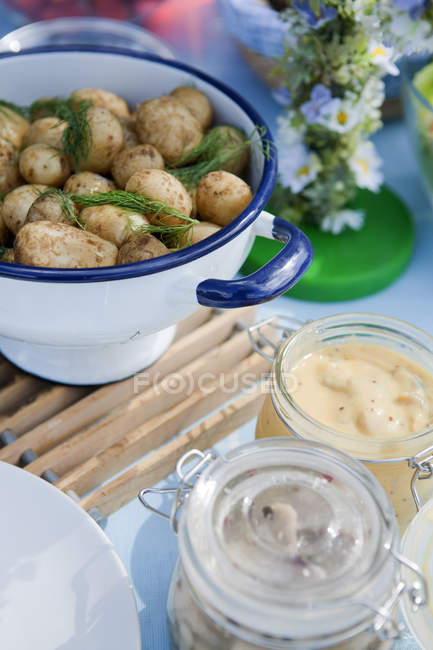Свежий картофель и сельдь в банке на столе — стоковое фото