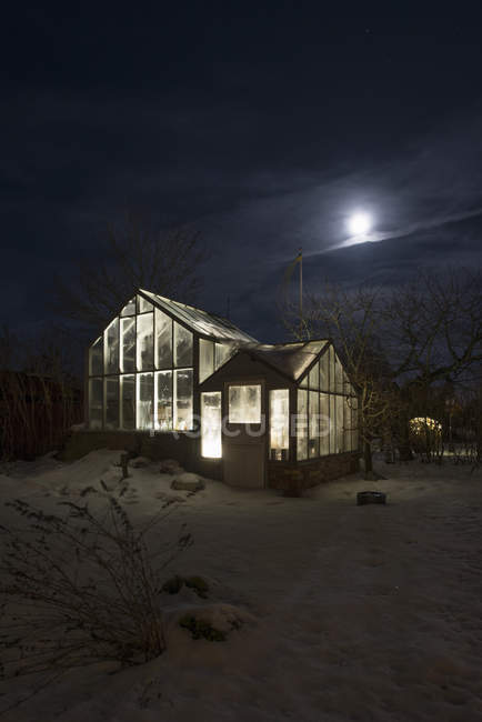 Außenseite des beleuchteten Gewächshauses bei Nacht im Winter — Stockfoto