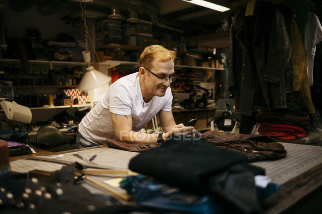Hombre maduro que trabaja en taller de cuero, concepto de pequeña empresa - foto de stock