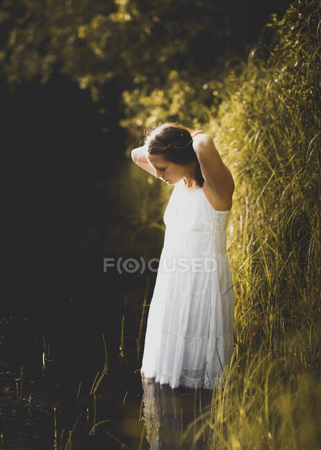 Woman wading in river, looking down — Stock Photo