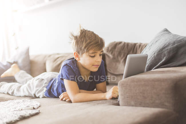 Menino no sofá jogando com tablet PC — Fotografia de Stock