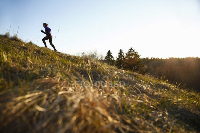 Mulher correndo para cima de uma colina, vista lateral — Fotografia de Stock
