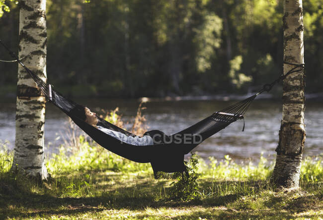 Woman resting in hammock near river — Stock Photo