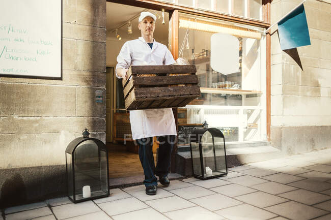Butcher in uniform carrying crate — Stock Photo