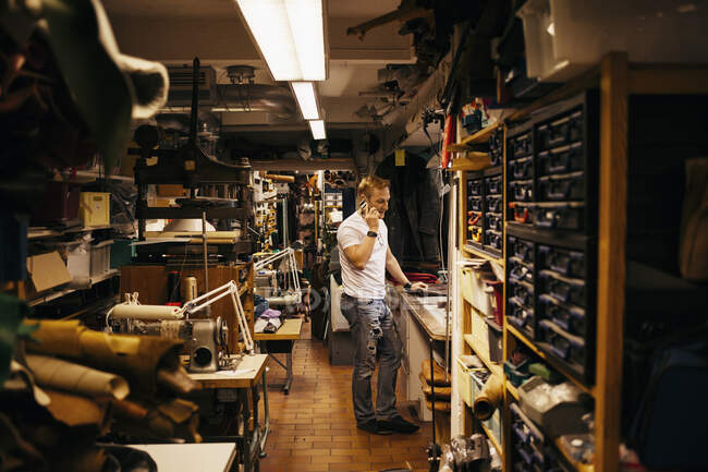 Homme mûr avec des cheveux blonds travaillant dans un atelier de cuir — Photo de stock