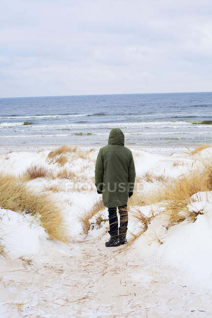 Rückansicht eines erwachsenen Mannes, der im Winter am Strand steht — Stockfoto