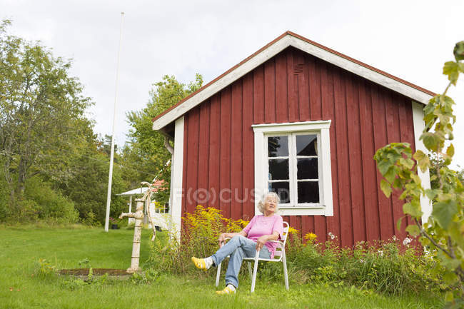 Старшая женщина отдыхает в кресле на открытом воздухе — стоковое фото