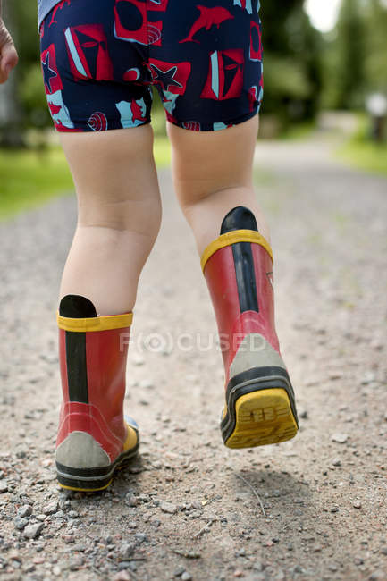 Menino caminhando em botas de borracha — Fotografia de Stock
