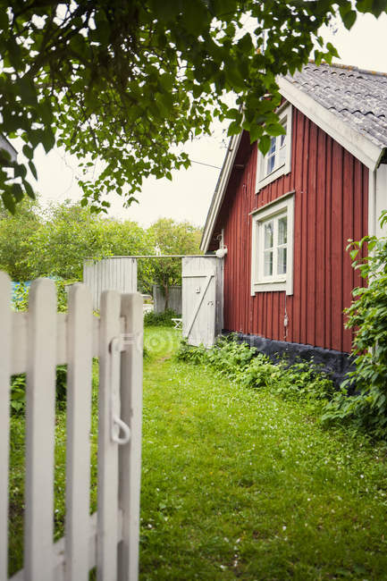 Jardin par maison en bois rouge, scène rurale — Photo de stock
