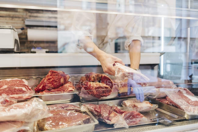 Açougueiro organizando carne em exposição, foco seletivo — Fotografia de Stock