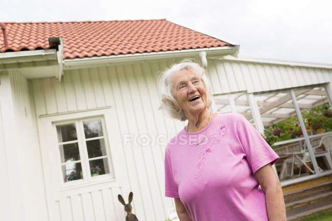 Старшая женщина смеется и смотрит в сторону во дворе — стоковое фото