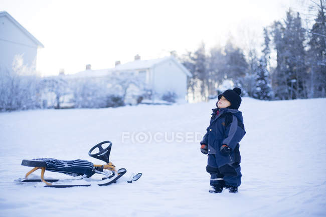 Vue latérale du jeune garçon debout sur la neige — Photo de stock