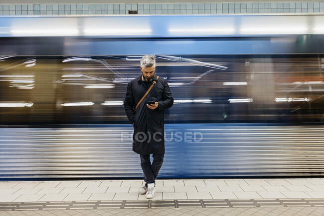 Homem textando na estação ferroviária — Fotografia de Stock