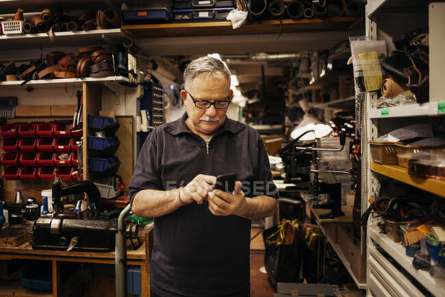 Homem sênior em óculos trabalhando em oficina de couro — Fotografia de Stock