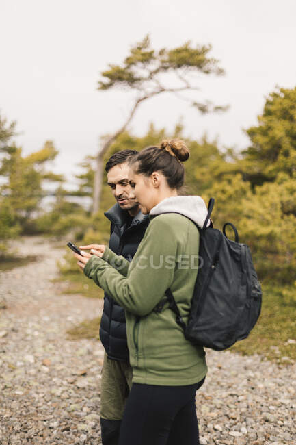 Couple de randonneurs utilisant un téléphone intelligent — Photo de stock
