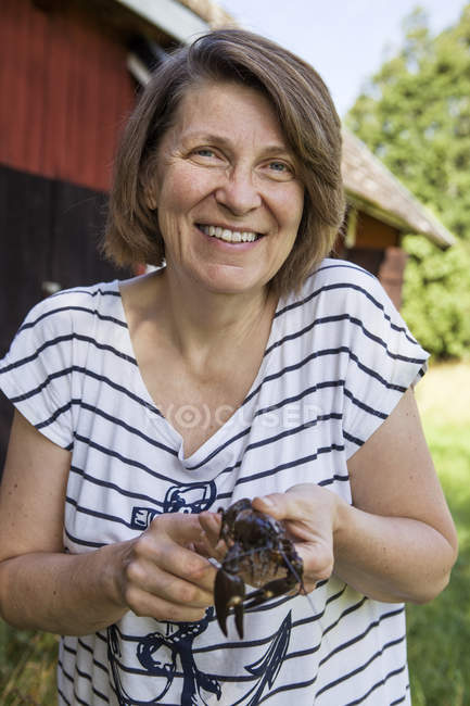 Lächelnde Frau hält Krebse in der Hand und blickt in die Kamera — Stockfoto