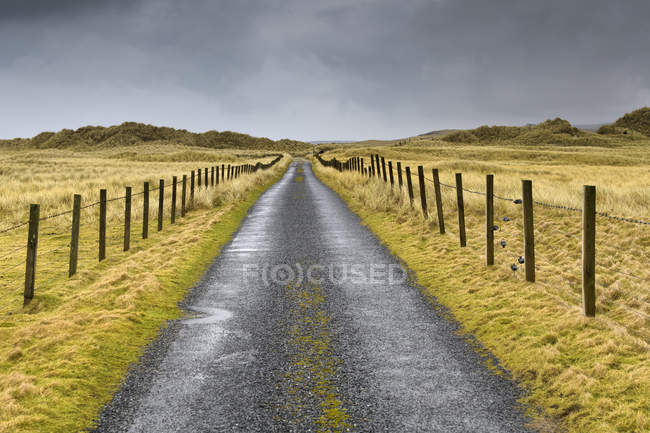 Camino rural bajo nubes de tormenta en Shetland, Escocia - foto de stock