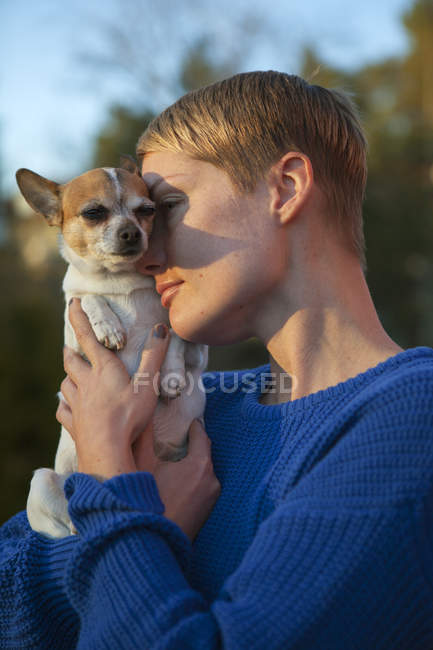 Mujer adulta que sostiene al perro, concéntrese en el primer plano - foto de stock