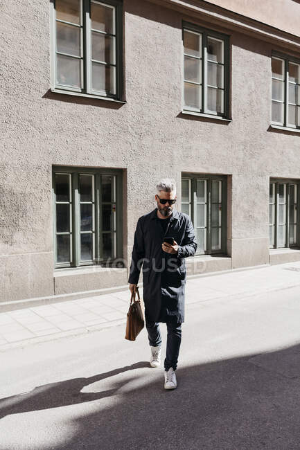 Mann läuft mit Smartphone in Stockholm die Straße entlang — Stockfoto