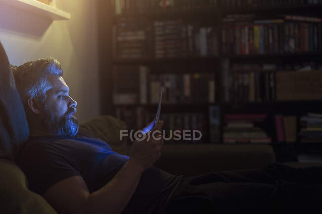 Человек на диване с планшетным компьютером — стоковое фото