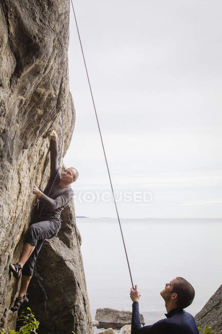 Двое мужчин взбираются на скалу, фокусируются на переднем плане. — стоковое фото