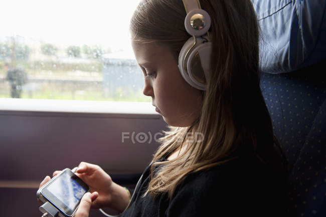 Девушка сидит в поезде и использует мобильный телефон — стоковое фото