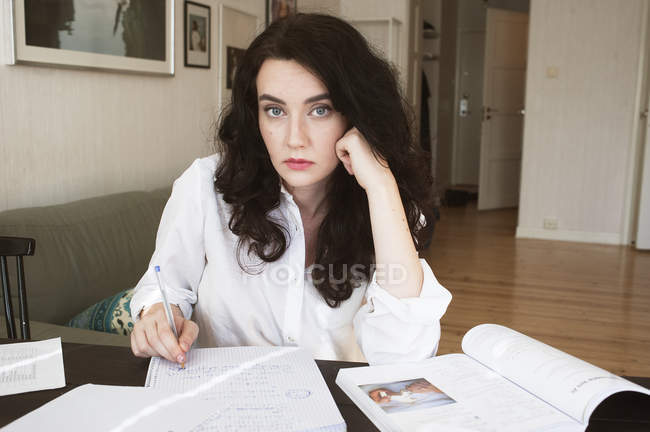 Молодая женщина сидит за столом и учится — стоковое фото