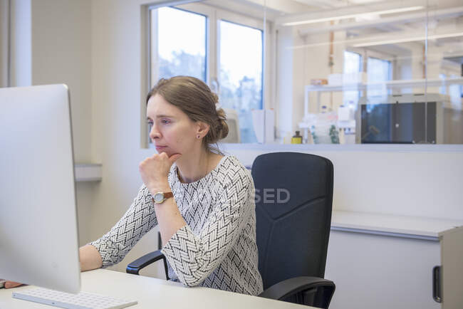 Mulher focada usando o computador enquanto se senta na mesa no escritório — Fotografia de Stock