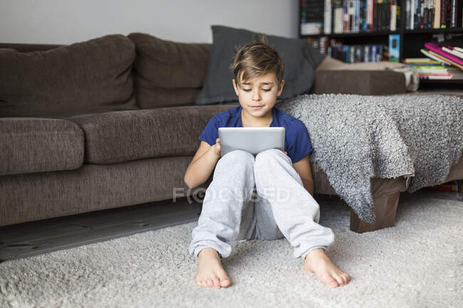 Мальчик на полу играет с планшетным компьютером — стоковое фото