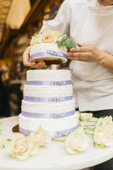 Vista cortada do padeiro juntando bolo — Fotografia de Stock