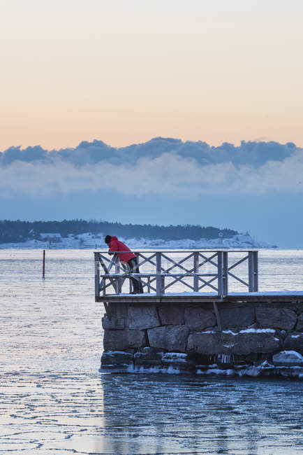 Teenage boy standing on pier at sunset — Stock Photo