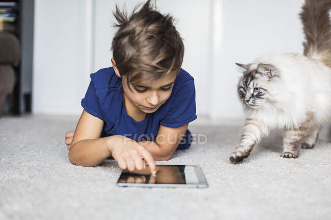 Мальчик лежит на полу с планшетным компьютером — стоковое фото