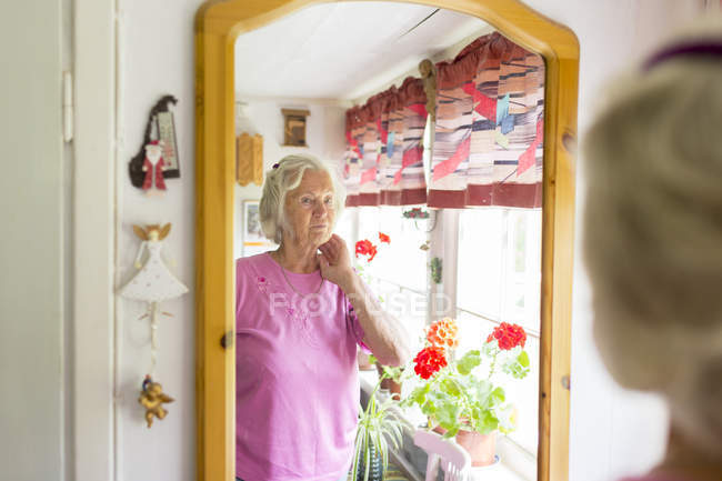 Donna anziana guardando allo specchio, messa a fuoco selettiva — Foto stock