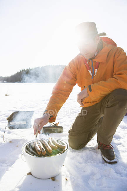 L'uomo grigliate salsicce durante l'inverno — Foto stock