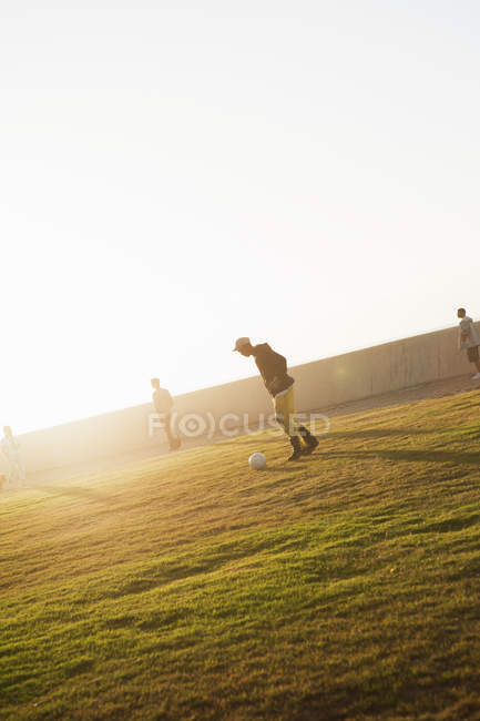 Four teenage boys playing soccer in park — Stock Photo