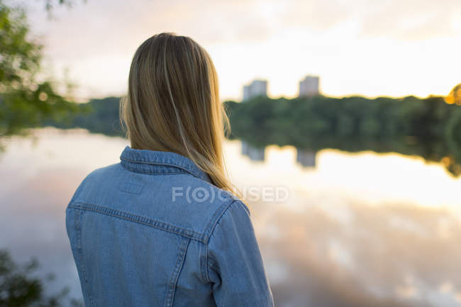 Teenage girl standing at edge of lake — Stock Photo