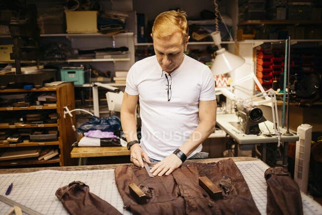 Focused mature man working in leather workshop — Stock Photo