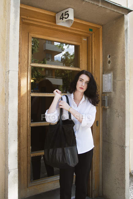 Portrait of young woman standing by door — Stock Photo