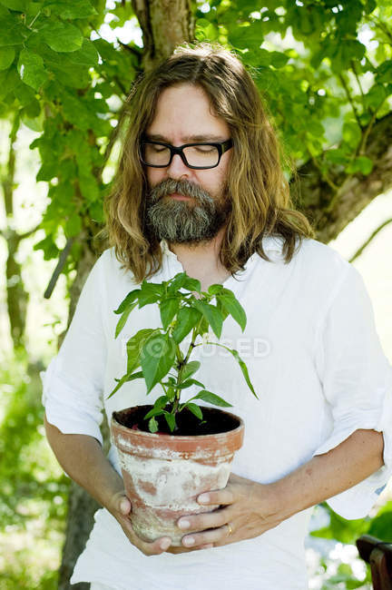 Uomo in piedi con gli occhi chiusi in possesso di pianta in vaso — Foto stock