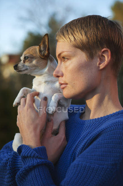 Середня доросла жінка тримає собаку, фокус на передньому плані — стокове фото