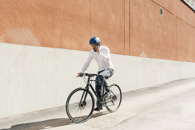 Мужчина разговаривает по смартфону во время езды на велосипеде — стоковое фото