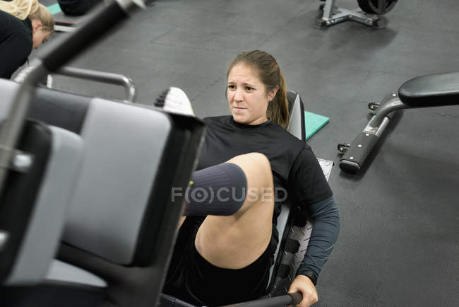 Young woman exercising on leg press machine — Stock Photo