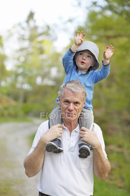 Homme portant petit-fils sur les épaules, se concentrer sur le premier plan — Photo de stock