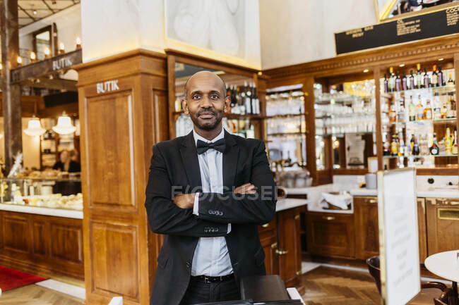 Waiter at bakery standing with crossed arms and looking at camera — Stock Photo