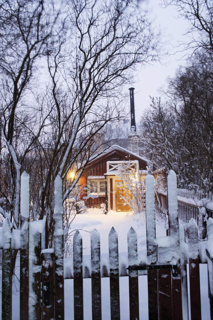 Освещенный красный дом в вечернее время зимой — стоковое фото