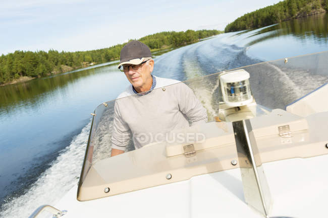 Homme âgé en vêtements décontractés conduisant bateau à moteur — Photo de stock