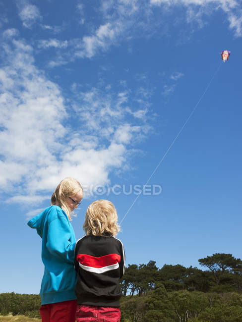 Low angle view of two sisters flying kite — Stock Photo