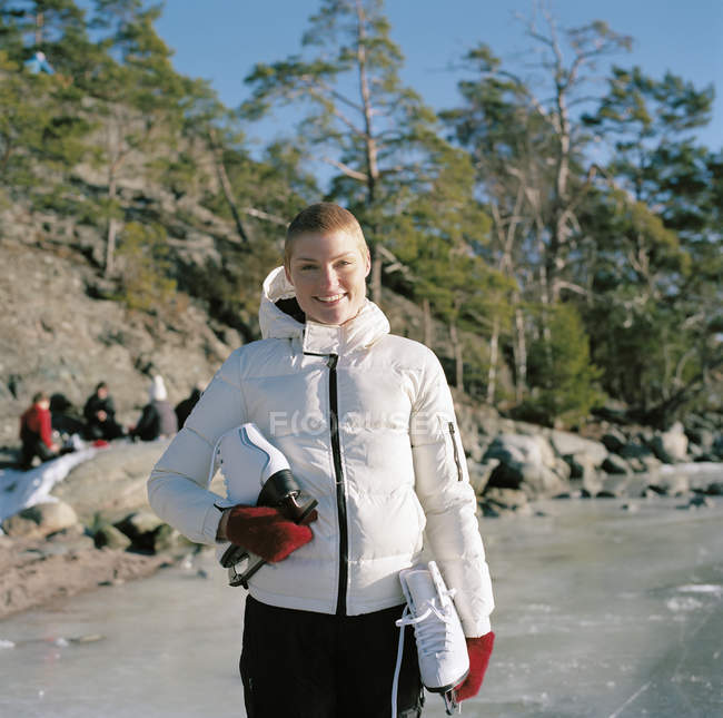 Portrait of mid adult woman holding ice skates — Stock Photo